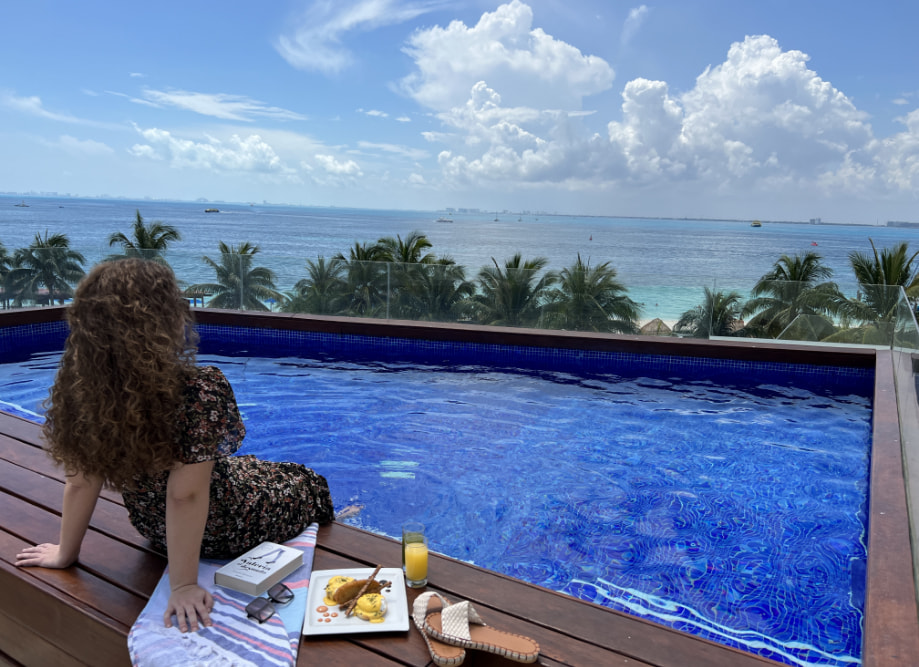 Mujer sentada en la terraza con alberca privada y vistas al mar