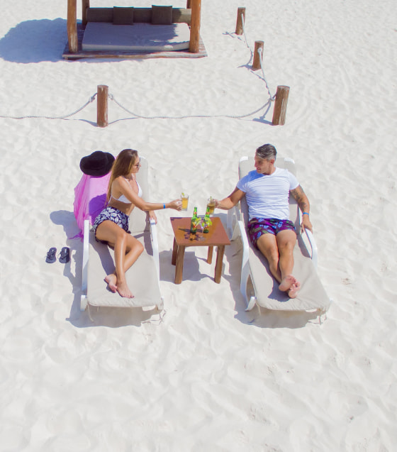 Clients in hammocks on the beach with Balinese bed behind them