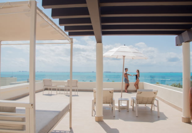 Terraza con sombrilla, hamacas y sofá con vistas al mar