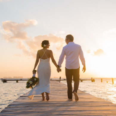 Bride and groom walking along one of Isla Mujeres' piers