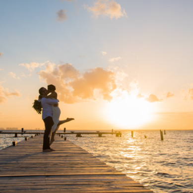 The bride and groom kissing in front of the coast of Isla Mujeres.