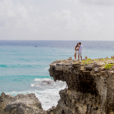 A bride and groom kissing on a cliff on Isla Mujeres