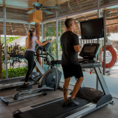 Gimnasio con vistas a la piscina y los jardines del hotel