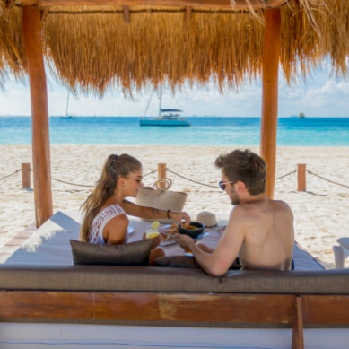 Pareja disfrutando de un snack en las palapas frente al mar