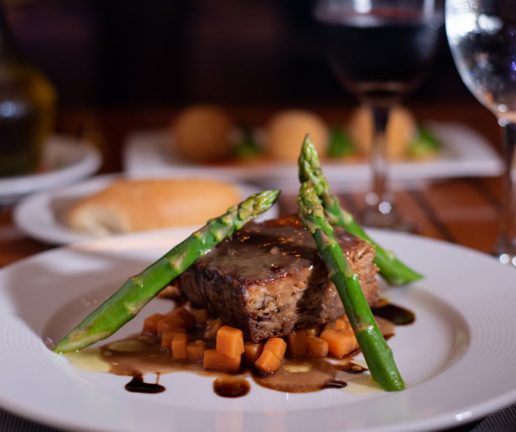 Porción de carne con zanahorias y espárragos verdes en salsa