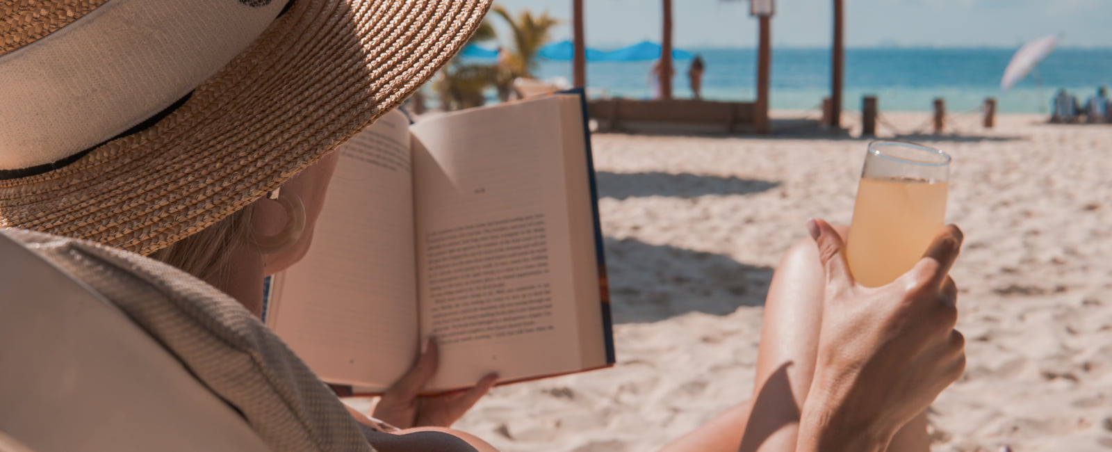 Cliente en la hamaca con una copa de champagne leyendo un libro