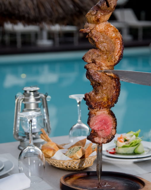 Waiter cutting roast meat at the table