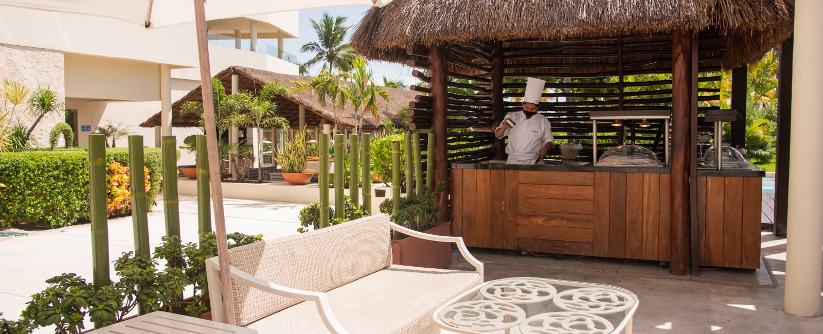 Sofa with small table and bar with a chef cooking