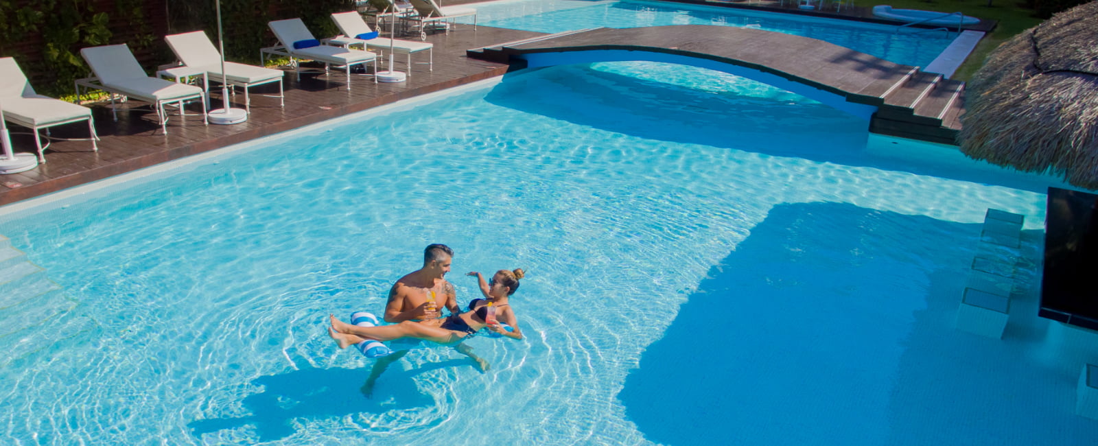 Pareja bañandose con cocktails en la mano en la piscina