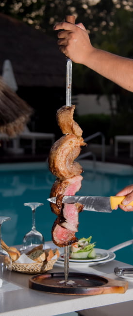 Grilled meat on skewers served by a waiter