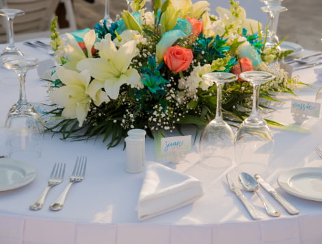 Flowers, cutlery, plates, glasses of a banquet table