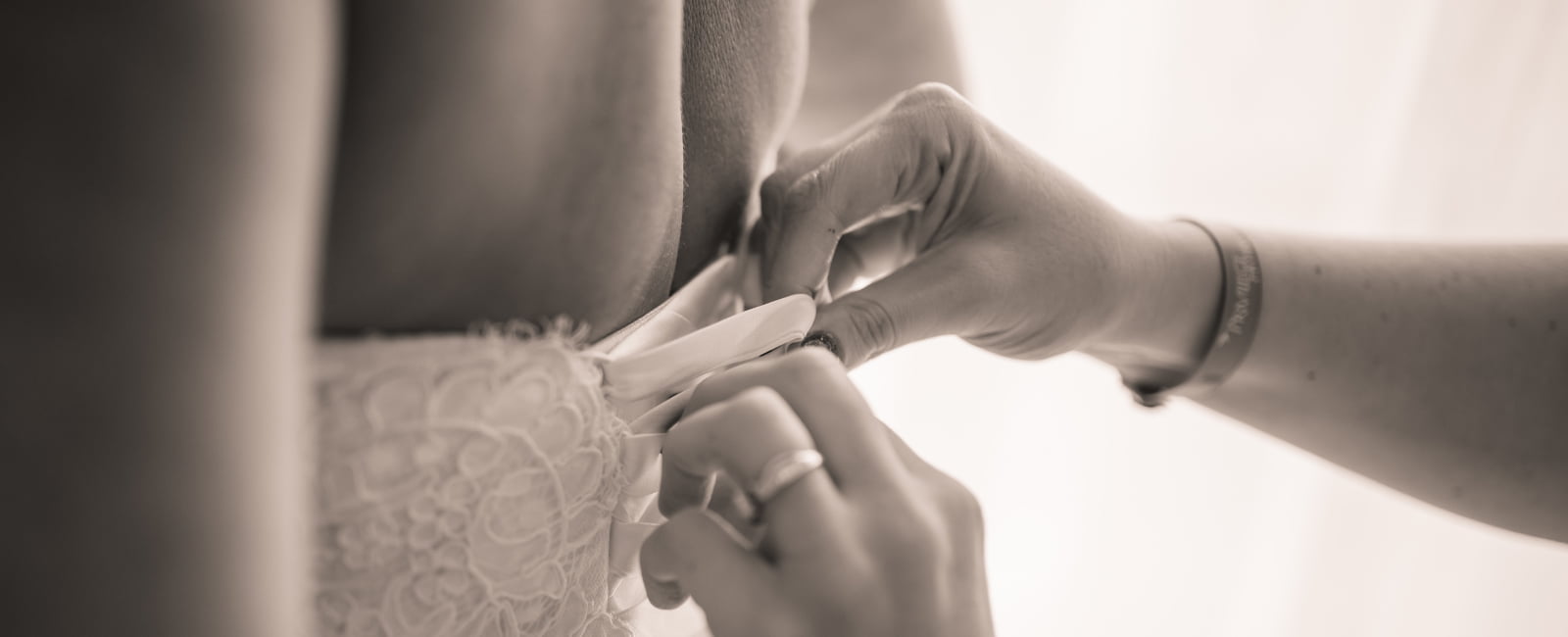 Hand dressing the bride's dress buttons.